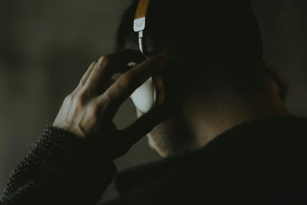 A close-up, moody shot of a man listening to music with headphones.
